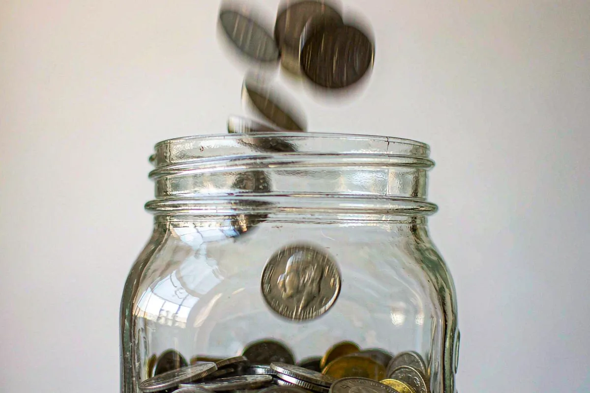Coins dropping into a savings jar