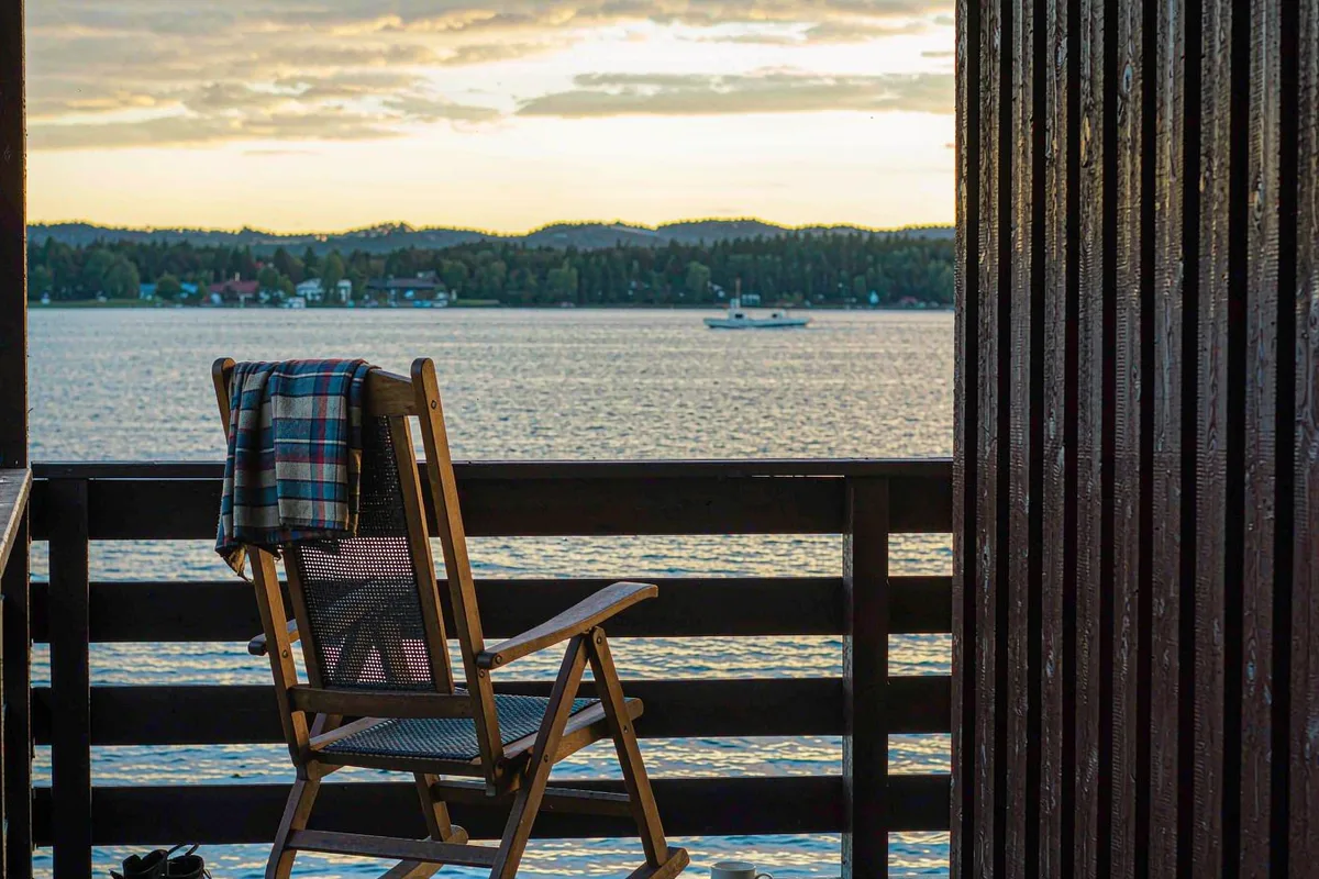 Wooden rocking chair on a porch overlooking a calm lake