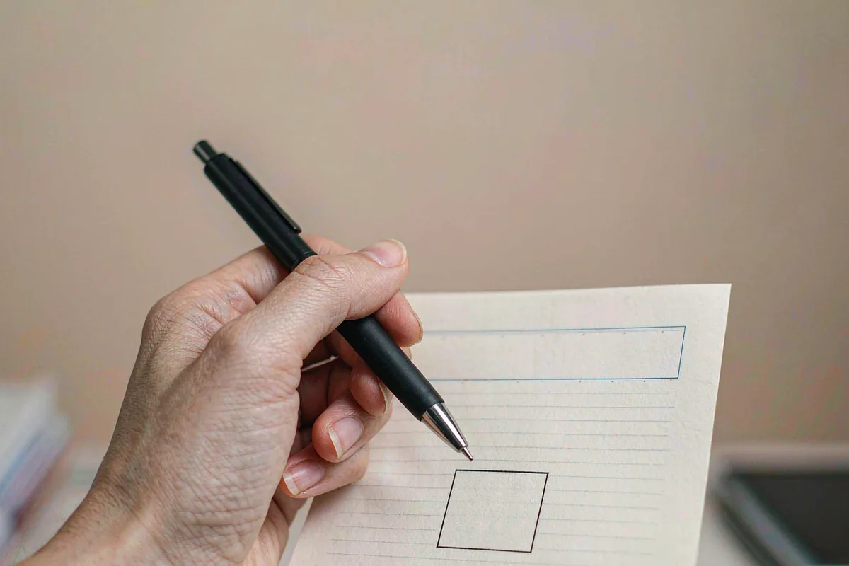 Hand holding a pen over a document with a checkbox