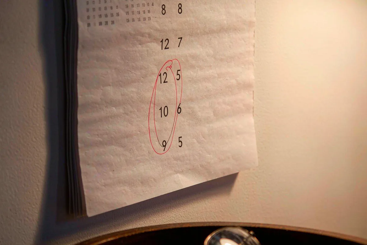 Wall calendar with a circled date and reading glasses