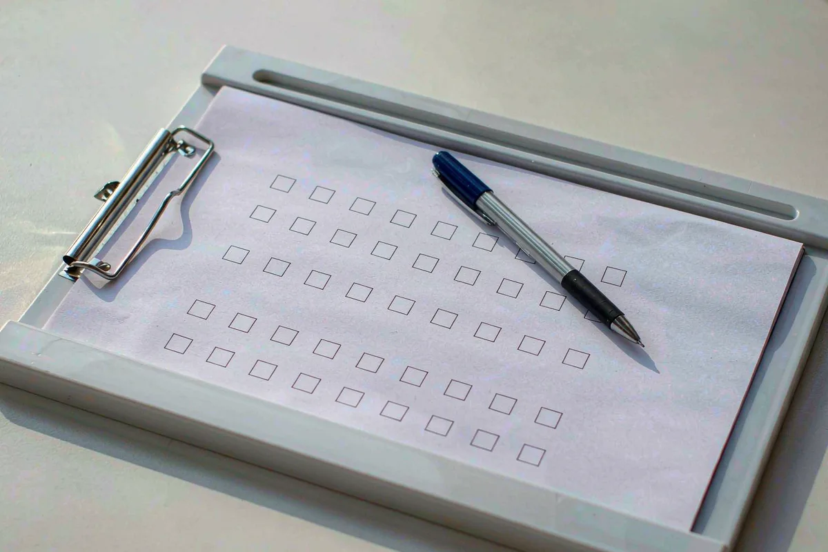 Clipboard holding a checklist page with a pen