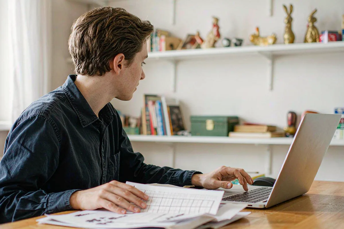 Person reviewing a printed financial statement beside a laptop