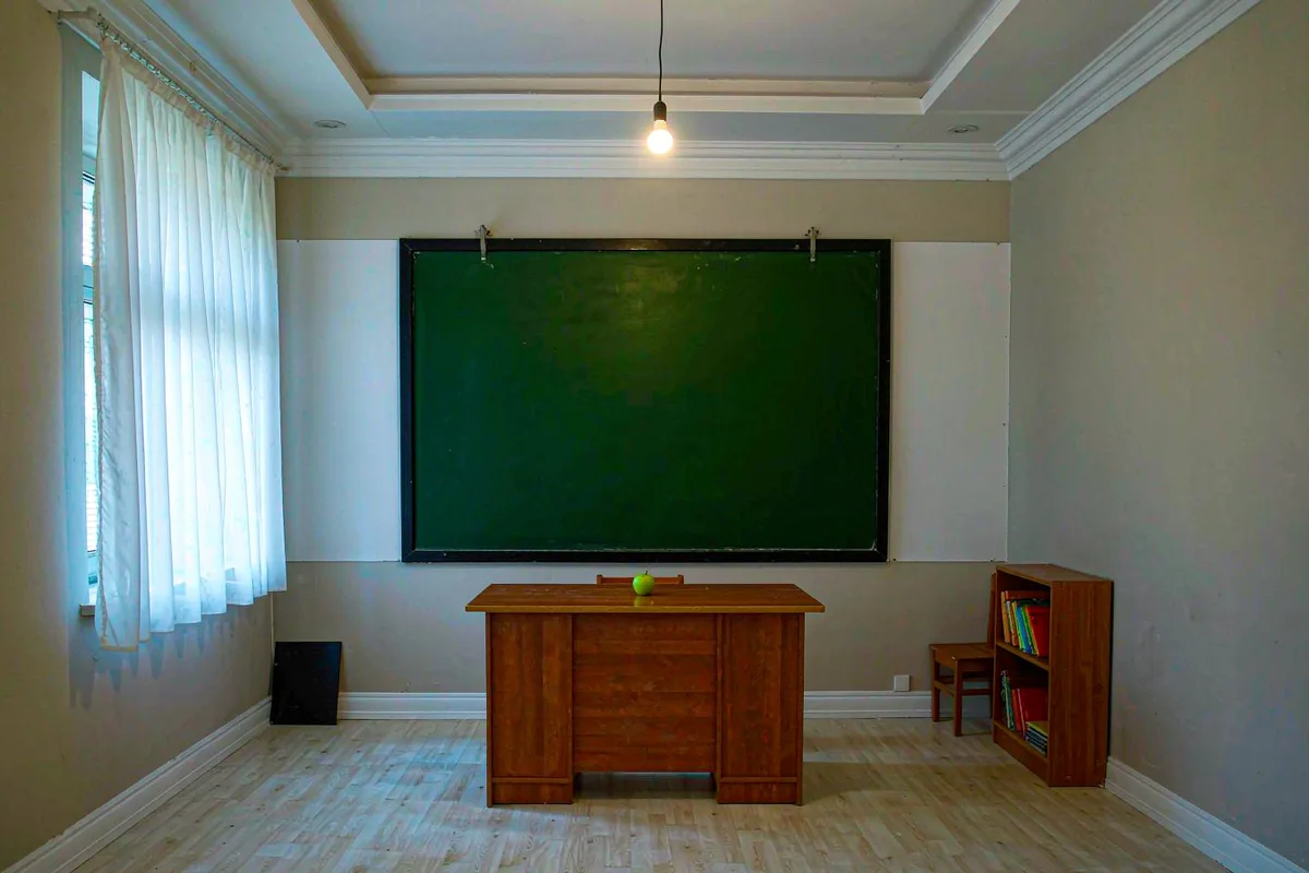 Empty classroom with a chalkboard and teacher desk