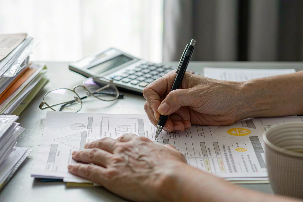 Hands completing forms with a calculator