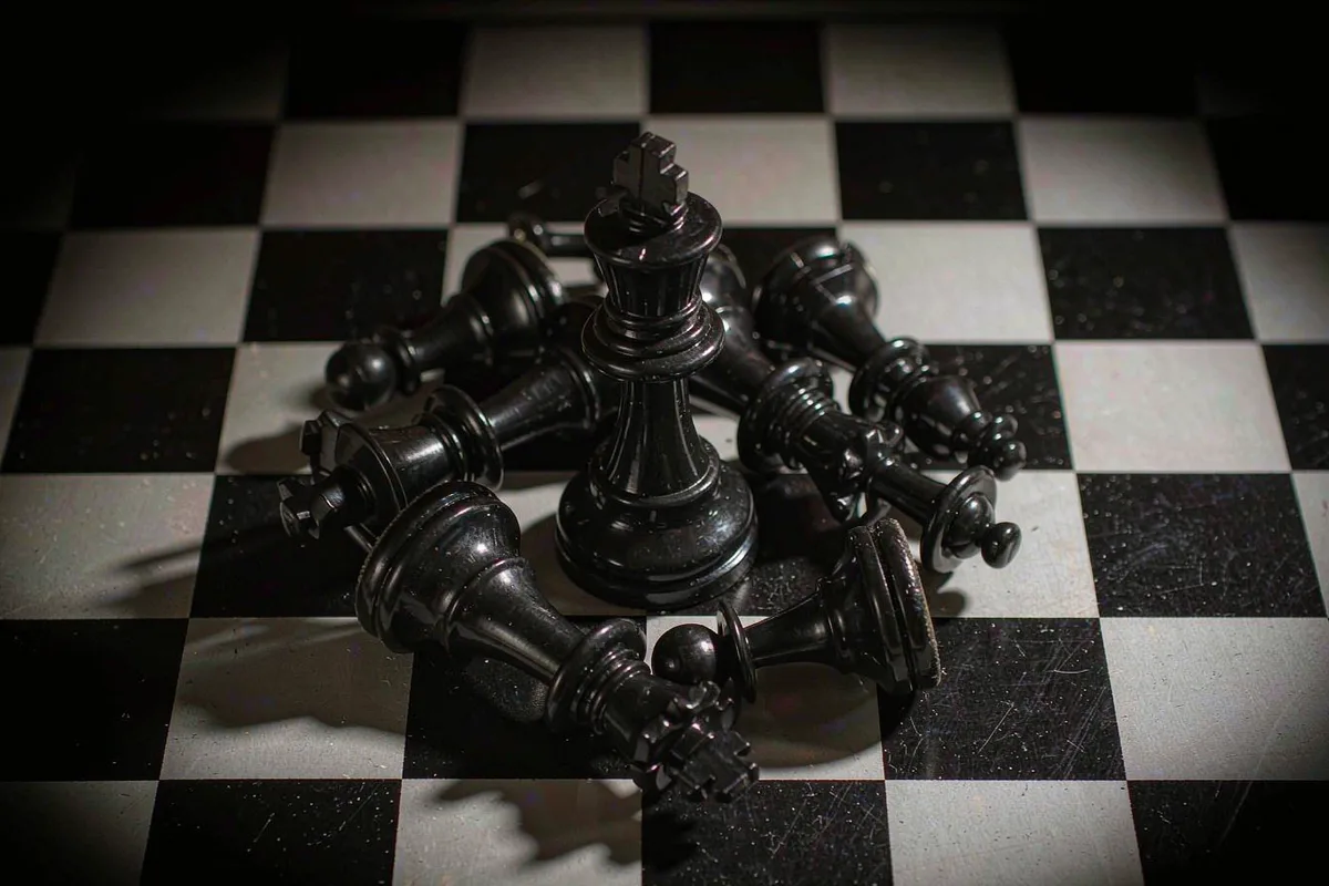 Fallen chess pieces scattered around a standing king
